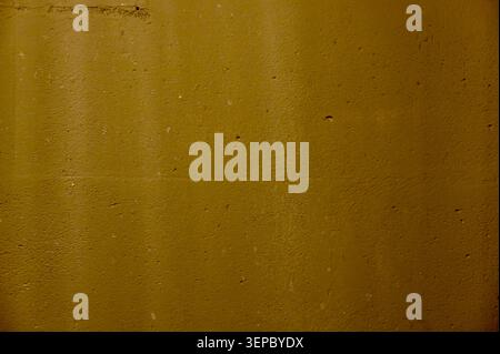 ​A beautiful horizontal macro texture shot of a solid mustard yellow concrete wall with a fine grainy surface. The composition is entirely filled by t Stock Photo