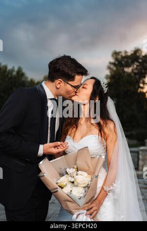 Interracial wedding couple kissing holding bouquet Stock Photo