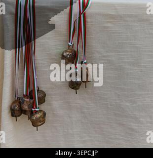 Traditional Bulgarian forged bells adorned with colorful ribbons are displayed against a light fabric background, highlighting their unique design and Stock Photo