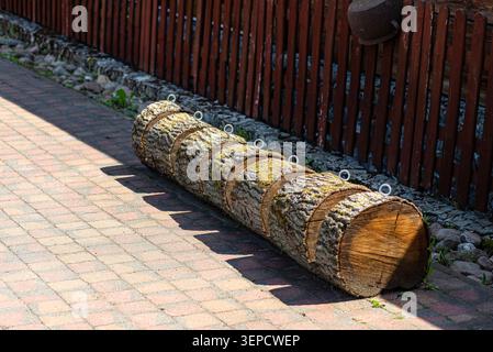 Rustic bike rack made from a split log provides outdoor parking next to a fence Stock Photo