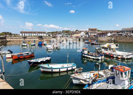 harbour scene at Porthleven in Cornwall, showing small fishing boats and leisure vessels moored on calm water. White and stone buildings line the Stock Photo