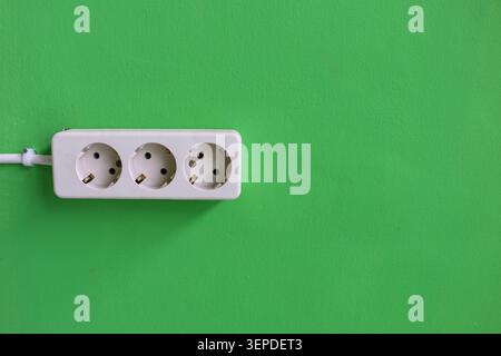 White Triple Electrical Power Outlet on Green Wall Background with Copy Space, Household Electricity Socket Installation and Energy Connection Concept Stock Photo