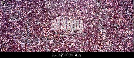 Red porphyry stone texture in macro view, showing imperial purple rock, mineral crystals and an abstract natural geological surface. Stock Photo