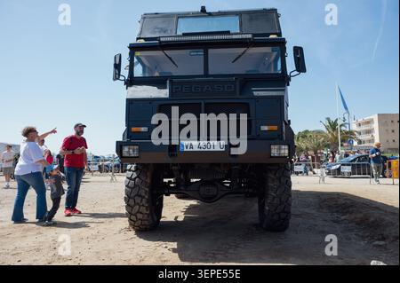 Eye level front view of a massive black vintage Pegaso 3046 overland expedition truck camper with people looking at it on a sunny day. Stock Photo