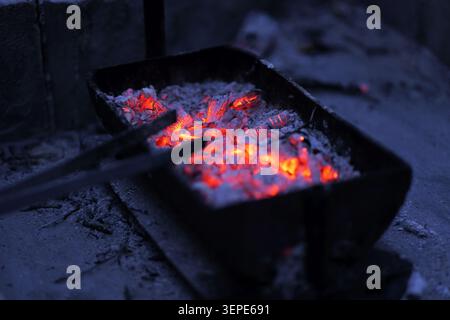 Hot charcoal glowing with orange light forming a warm bed of embers and ashes within a metal barbecue pit, emphasizing heat, warmth, cooking, and prep Stock Photo