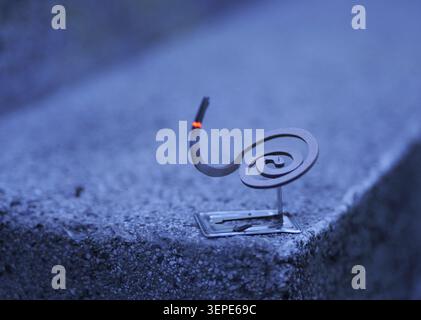Spiral mosquito coil burning with glowing orange ember and curling smoke at dusk, outdoor repellent protecting against insects on a patio or garden du Stock Photo