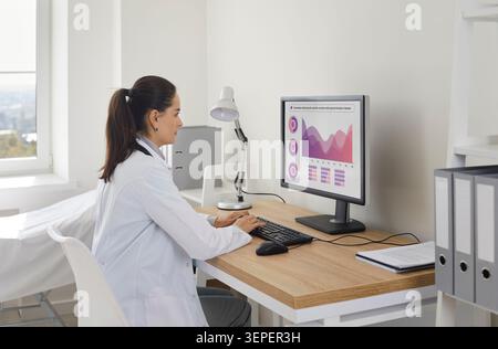 Doctor analyzing medical data on computer in clinic office, healthcare review Stock Photo