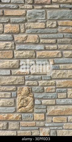 Rough cut stones forming a textured wall surface with a decorative stone carving Stock Photo