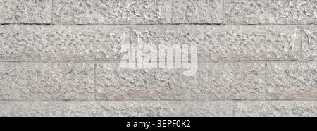 Grey rough stone wall featuring a textured masonry surface and repeating pattern Stock Photo