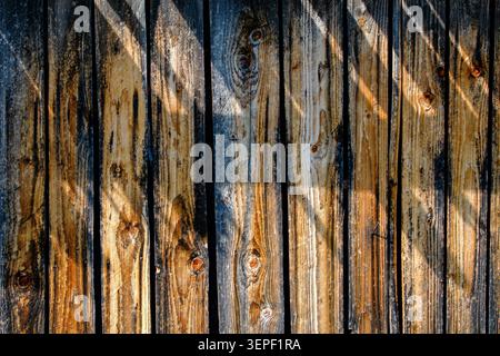 Rustic weathered wood fence texture with sunlight and shadow play natural timber background for outdoor design and vintage concepts. Close up. Stock Photo