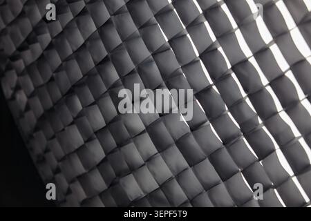 High-key macro photograph of a professional photographic honeycomb grid. The black mesh pattern is brightly and evenly illuminated, with all cells fil Stock Photo