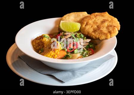 Strong beef broth with vegetables and beef on a deep white plate. Isolated on black background. Stock Photo