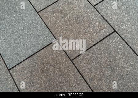 Close-up background texture of grey concrete paving slabs with diagonal seams, rough surface, natural color variation, and urban pavement pattern Stock Photo