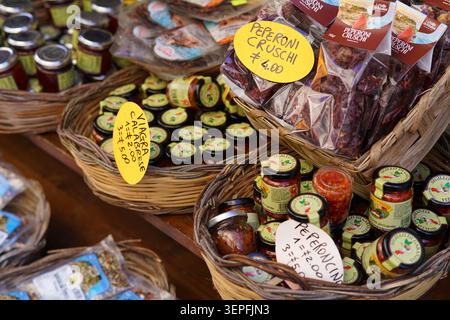 Traditional Calabrian food stall with wicker baskets full of Peperoni Cruschi, Nduja and homemade jars at a market in Tropea, Calabria Southern Italy. Stock Photo