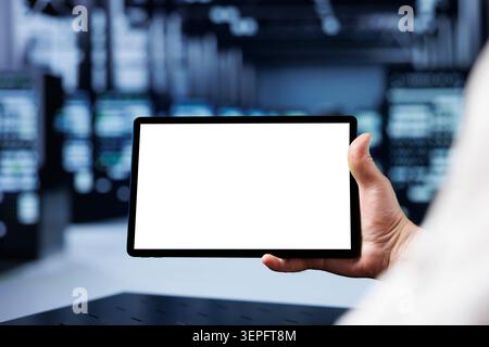 Adept IT developer using mockup tablet to check operational server rows, close-up; racks in computer network security data center providing processing and memory resources for several workloads. Stock Photo