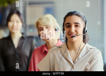 Portrait of diverse young adult and middle aged women wearing headsets, supporting customers in call center team office. Ideal for customer service, help desk, CRM marketing Stock Photo