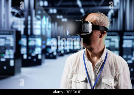 Old cloud computing business executive immersed in virtual reality at data center, doing equipment maintenance. Stock Photo