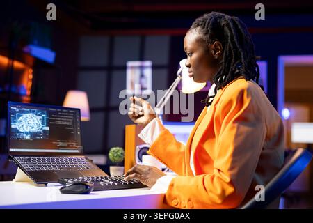 Programmer in living room office typing on keyboard, updating artificial intelligence neural networks, writing binary code scripts, freelancing system administrator upgrading high tech AI. Stock Photo