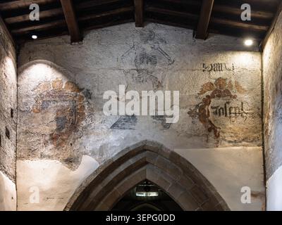Detailed look at the faded medieval wall paintings and stone archway inside the historic sanctuary of St Lawrence Church in Eyam Stock Photo
