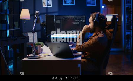 Frenzied programmer suffering from adhd illness, impatiently taping desk with fingers while writing code. Jittery IT expert doing multitasking in office, drinking coffee, listening music. Stock Photo
