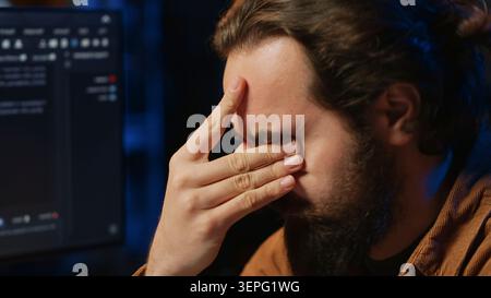 Disappointed computer scientist puzzled after being unable to remove all bugs while coding on workstation desktop. Teleworking IT specialist confused by troubling script errors. close up. Stock Photo