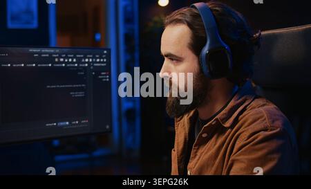 Computer scientist listening music while writing lines of code during remote job shift in home office. IT specialist enjoying audio podcast, coding on desktop PC. close up. Stock Photo