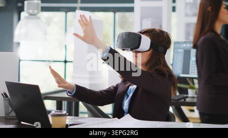 Architect designing project blueprints and plans with VR headset, using artificial intelligence to shape new property layout. Specialist working with virtual reality glasses at real estate agency. Stock Photo