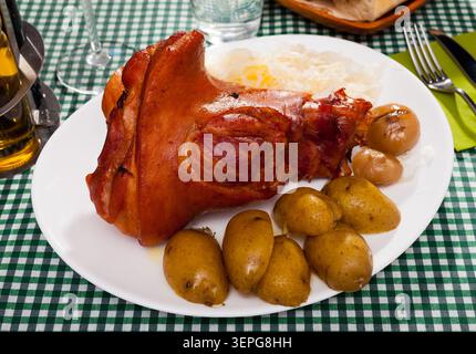 Appetizing pork knuckle and sauerkraut served with potatoes and onion Stock Photo