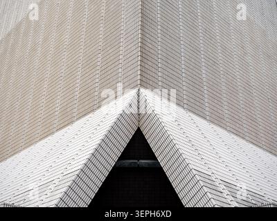 Abstract geometric architecture featuring triangular entrance framed by repeating ceramic tile patterns on Hong Kong Cultural Centre building. Minimal Stock Photo