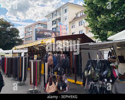 Pforzheim Germany - June 14, 2026 Mess A busy outdoor market stall displays rows of leather belts on racks and hanging handbags and backpacks beneath Stock Photo