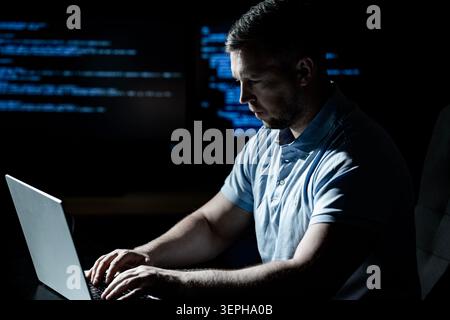 Programmer works in technology workplace. Programmer writes coding for software system. Programmer monitors network and cybersecurity threats Stock Photo