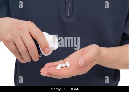 Close up of a man pouring white medical pills from a white bottle into his hand. Stock Photo