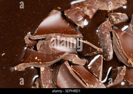 Dark chocolate chunks into liquid melted chocolate sauce background. Stock Photo