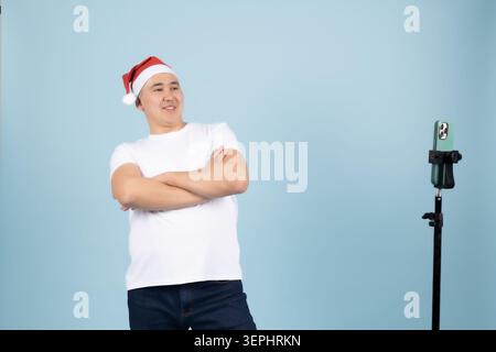 Man in a santa hat standing with arms crossed next to microphone Stock Photo