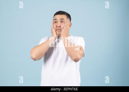 Young man holding both hands near face looking surprised and Stock Photo