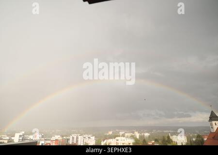 A rainbow is seen in the sky above a city Stock Photo