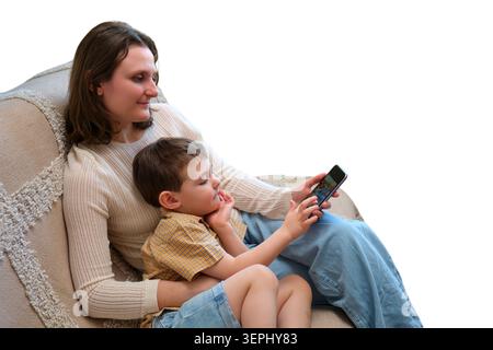 Mother and son looking at smartphone while sitting on sofa isolated on white background. Family using mobile technology for entertainment. Digital lif Stock Photo