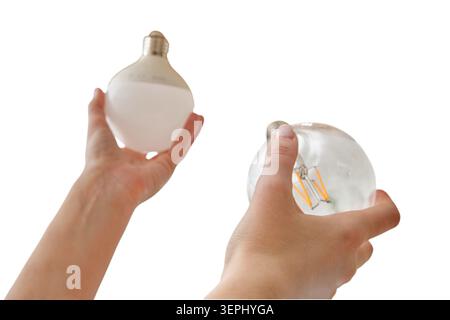 Woman comparing two different electric light bulbs. Hands holding frosted and transparent glass LED light bulb. Choice between energy efficient lighti Stock Photo