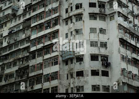 The outer corner of the Yick Cheong Building in Quarry Bay, Hong Kong, showing a rounded block section, weathered white concrete with red stripe detai Stock Photo