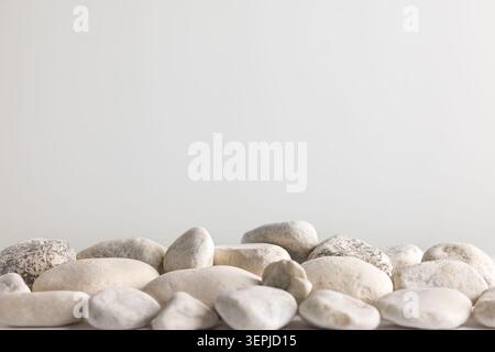 White pebble stones on pale background with large copy space for wellness spa and natural texture layout Stock Photo