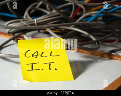 Reminder note to call network technician with messy cables background Stock Photo