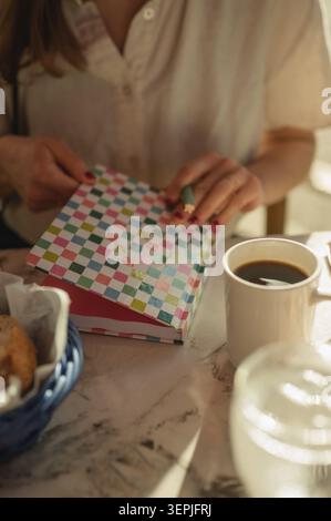 Close up of young woman writing in a colorful notebook at a cafe table Stock Photo