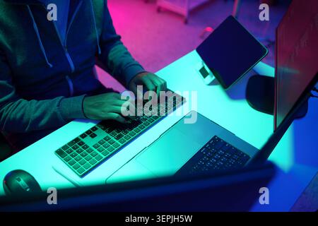 Person Typing on Keyboard in Neon Lit Computer Workspace Stock Photo