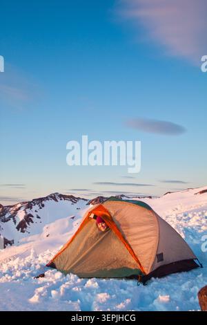 Adventurous woman sticker her head out of the tent, winter camping Stock Photo