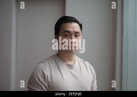 A serious young East Asian man looks at camera Stock Photo