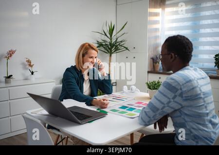 Businesswoman talking on phone during meeting with client Stock Photo