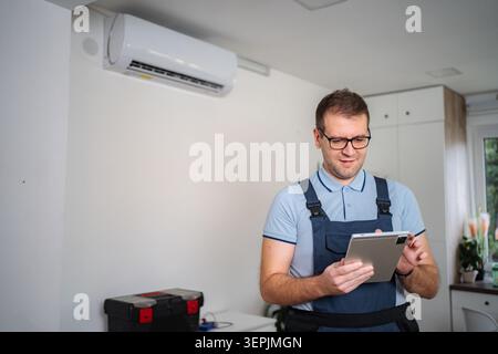 Technician checking air conditioner with digital tablet Stock Photo