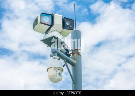 Smart surveillance camera and monitoring system mounted on pole against cloudy blue sky for traffic monitoring, public safety and smart city Stock Photo