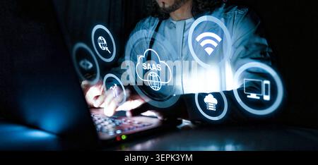 Individual using a laptop to explore Saas technology and digital services at night Stock Photo
