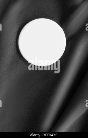 Round blank white button badge on black silk fabric background Stock Photo